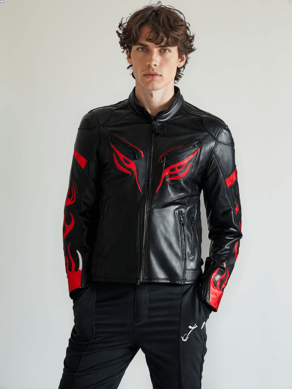 Side angle of a black leather motorcycle jacket, showing the red flame pattern on the sleeve, a partial view of the front zipper, and a contoured fit for comfort and protection.