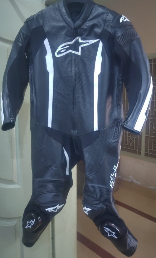 Black motorcycle suit with white accents on a stand against a neutral background