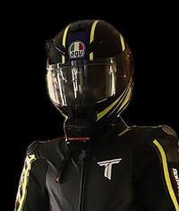 Person wearing a black motorcycle helmet with a clear visor and a black jacket on a black background