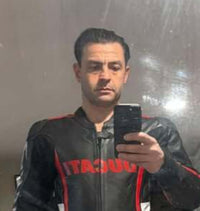 Person wearing a black jacket with red accents taking a mirror selfie.